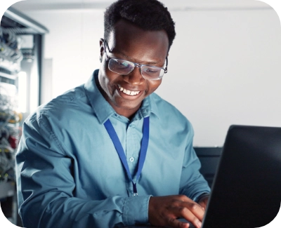 server technician smiling at at tablet while working on a laptop